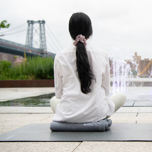 person sitting meditating relaxing on mexican style yoga blanket