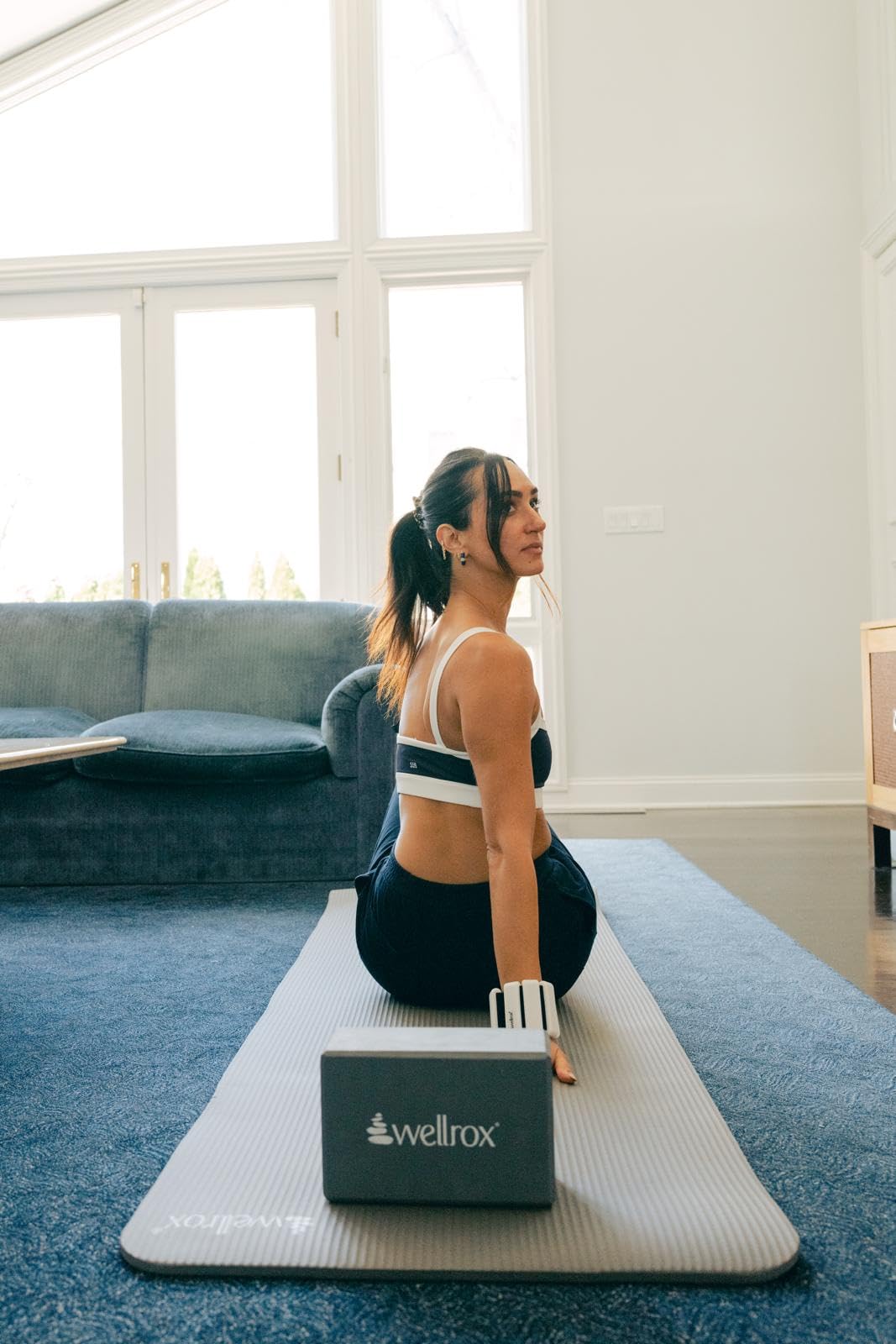 A person is doing yoga on a mat with a Wellrox yoga block