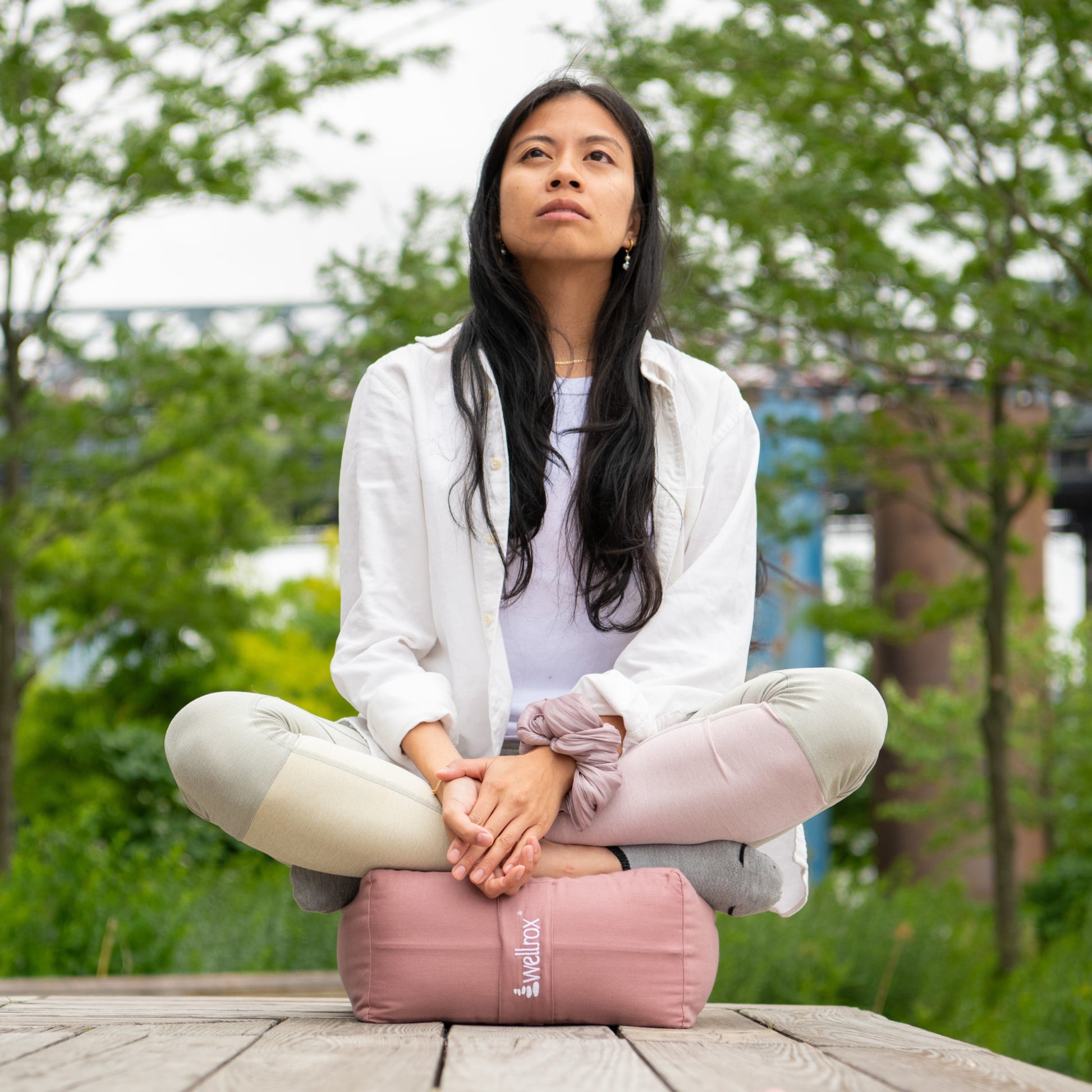 woman sitting on a rose indian cotton rectangular yoga bolster in a relaxing pose