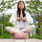 woman sitting on a rose indian cotton rectangular yoga bolster in a meditative pose