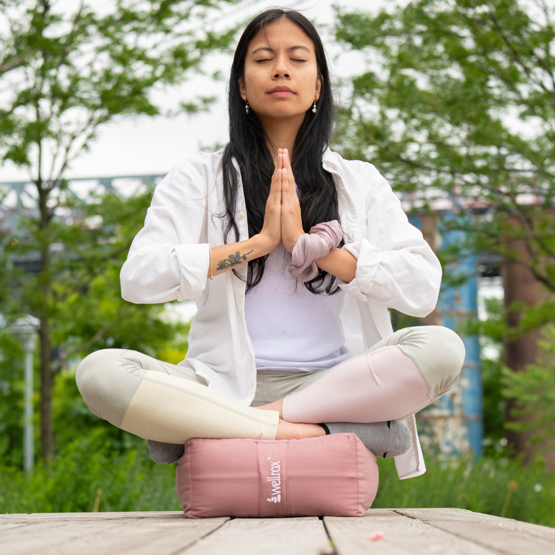woman sitting on a rose indian cotton rectangular yoga bolster in a meditative pose