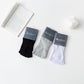 A set of toeless non-slip yoga socks in black, gray, and white colors